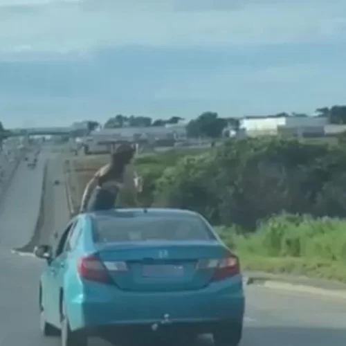 Mulher é flagrada sentada no teto solar de carro em movimento na BR-153 em Aparecida de Goiânia.