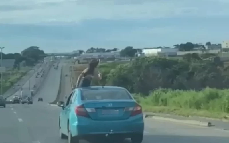 Mulher é flagrada sentada no teto solar de carro em movimento na BR-153 em Aparecida de Goiânia.